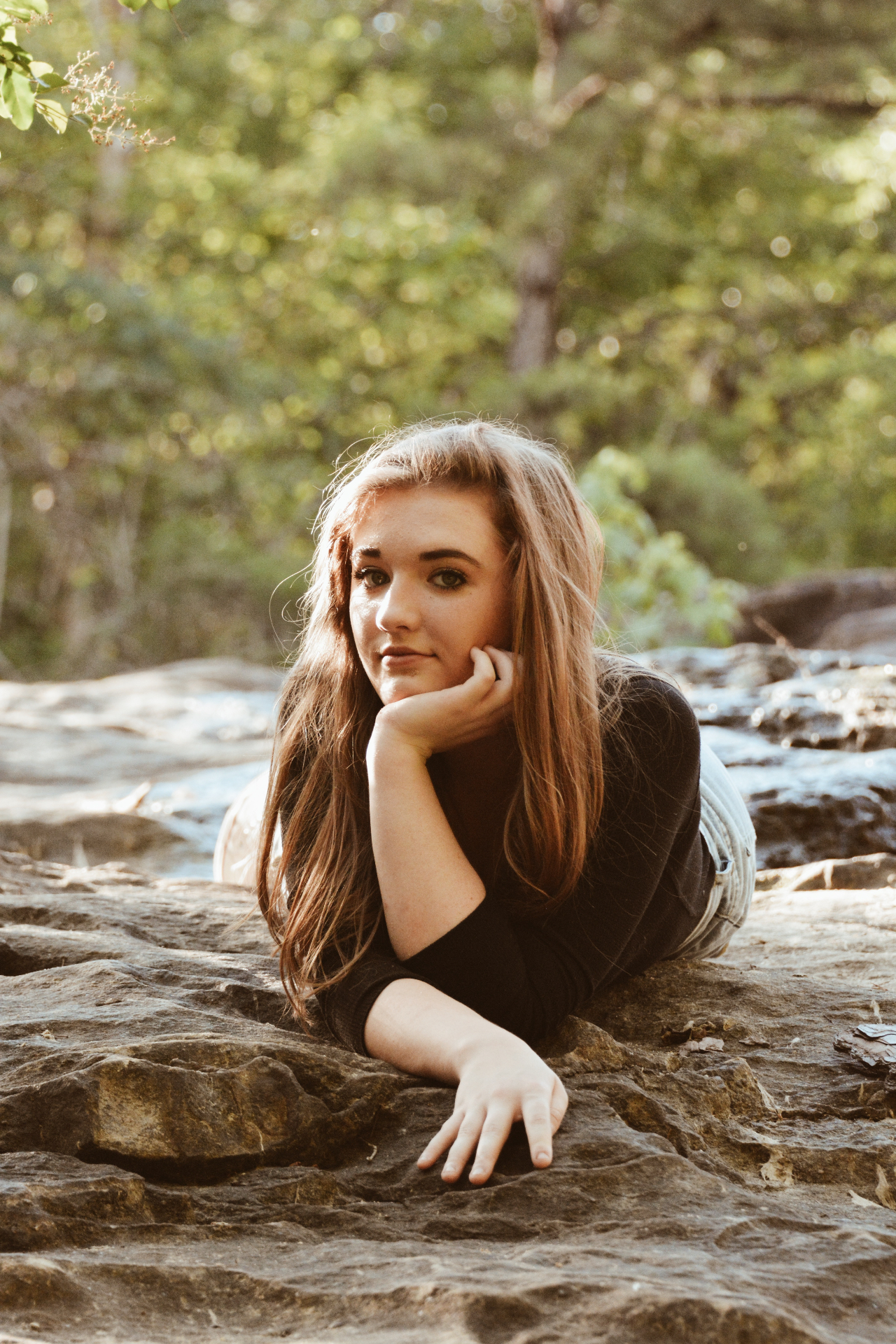 Young woman resting her chin in her hand on a rock