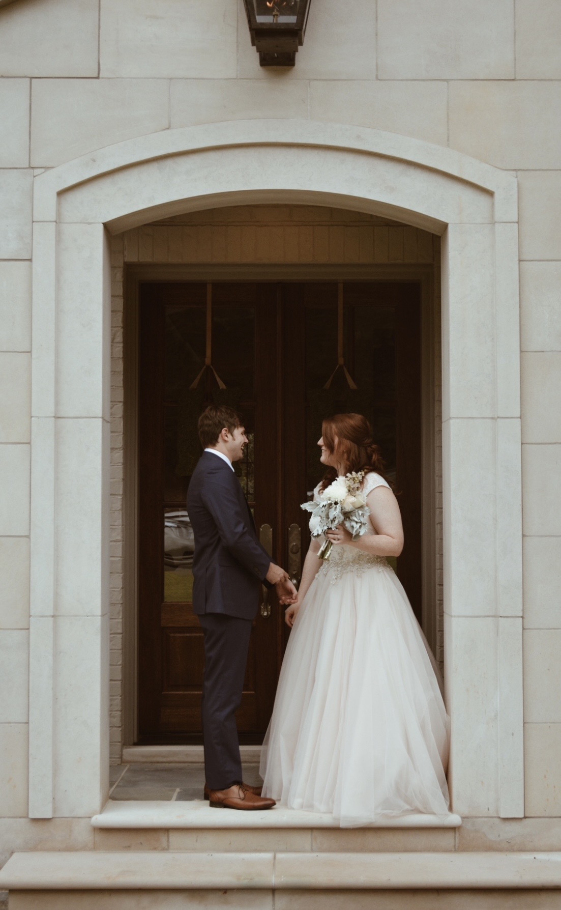 Bride and groom holding hands in a stone doorway