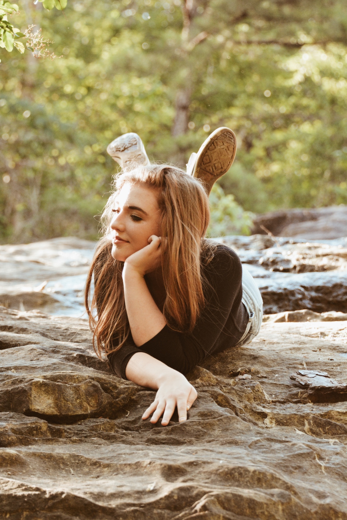 Young woman lying on a sunlit rock smiling softly