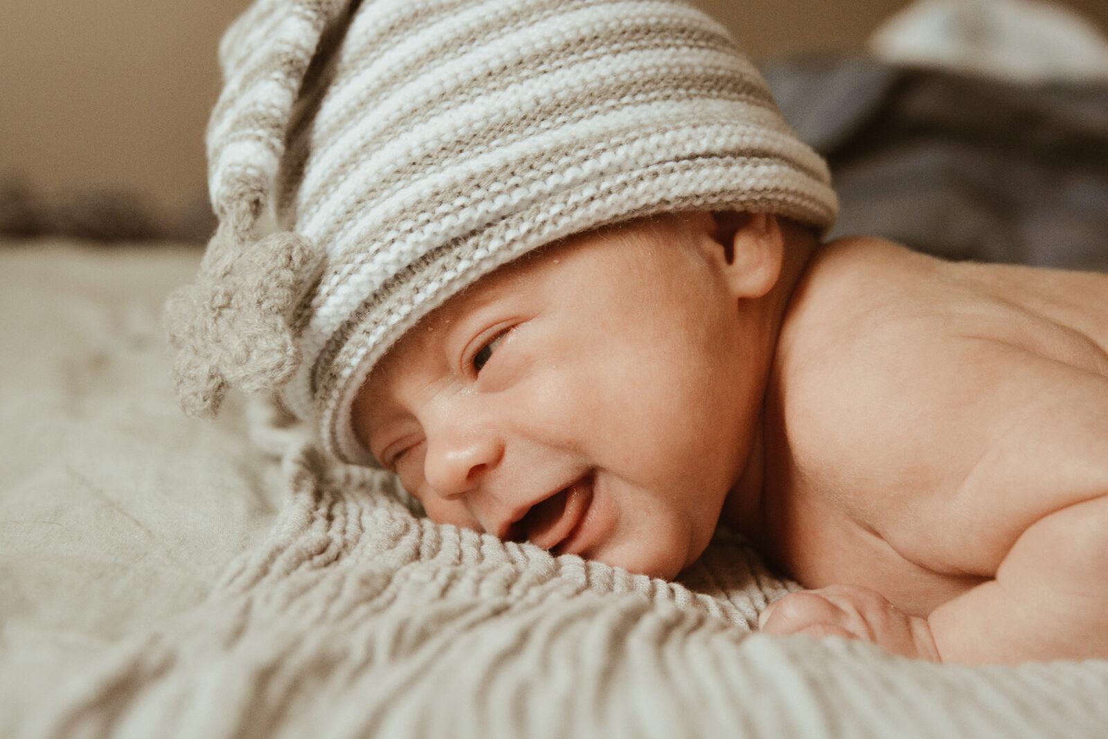 Newborn baby in a knit cap resting on a soft blanket